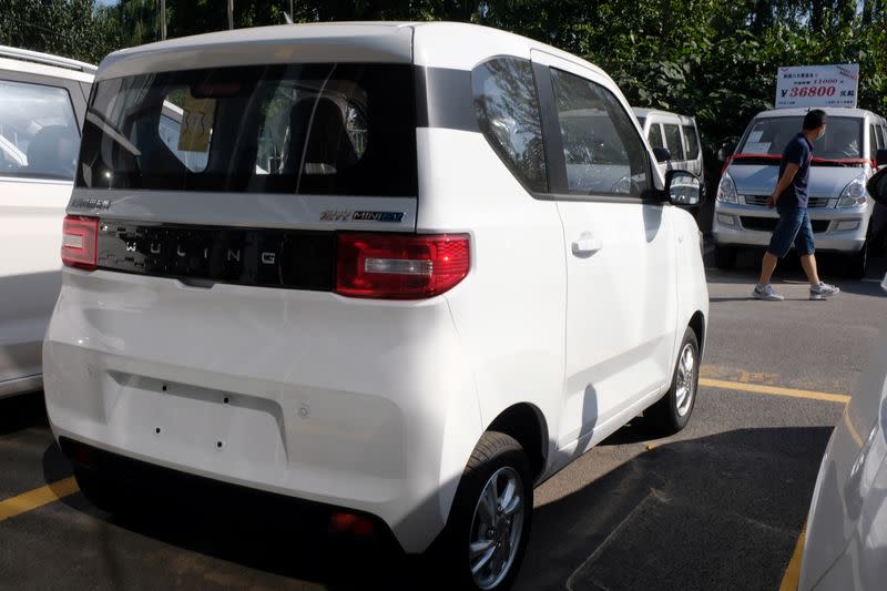 Man walks past a Wuling Hongguang MINI EV at a SAIC-GM-Wuling dealership in Beijing