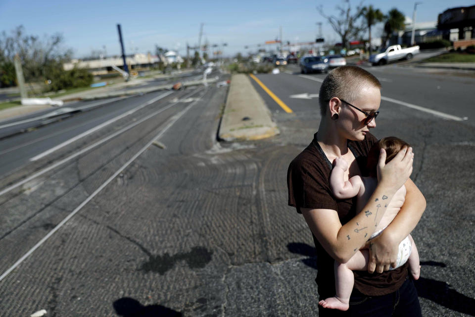 Kylie Strampe holds her four-month-old daughter, Lola, while surveying the damage from Hurricane Michael after riding out the storm in Callaway, Fla., Thursday, Oct. 11, 2018. (AP Photo/David Goldman)