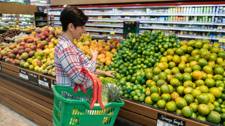 woman buying limes at grocery store