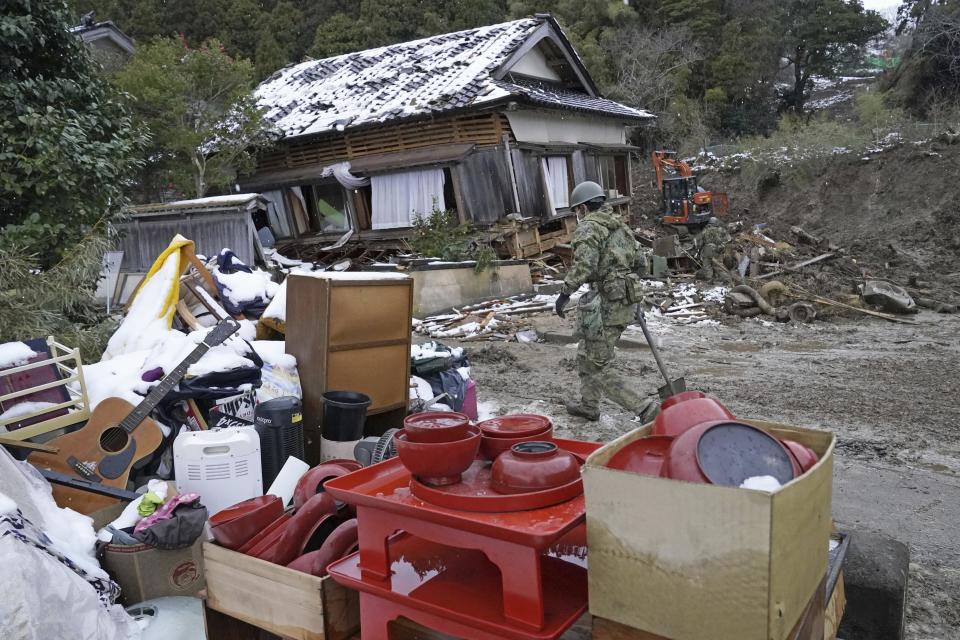 Housewares are gathered outside a fallen house as a member of Japan Self Defense Force searches the area in the earthquake-hit Suzu, Ishikawa prefecture, Monday, Jan. 8, 2024. Thousands of people made homeless overnight are living in weariness and uncertainty on the western coast of Japan a week after powerful earthquakes hit the region. (Kyodo News via AP)