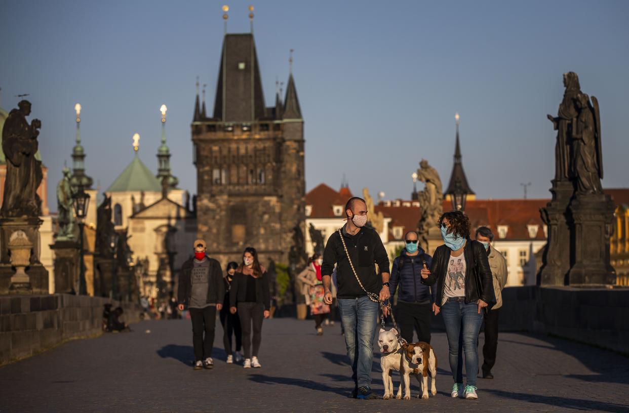A couple with face masks walk their dogs on the Charles bridge on April 20, 2020, in Prague, Czech Republic. The Czech government has begun partially easing the measures to slow down the spread of the pandemic COVID-19 disease during the lockdown.