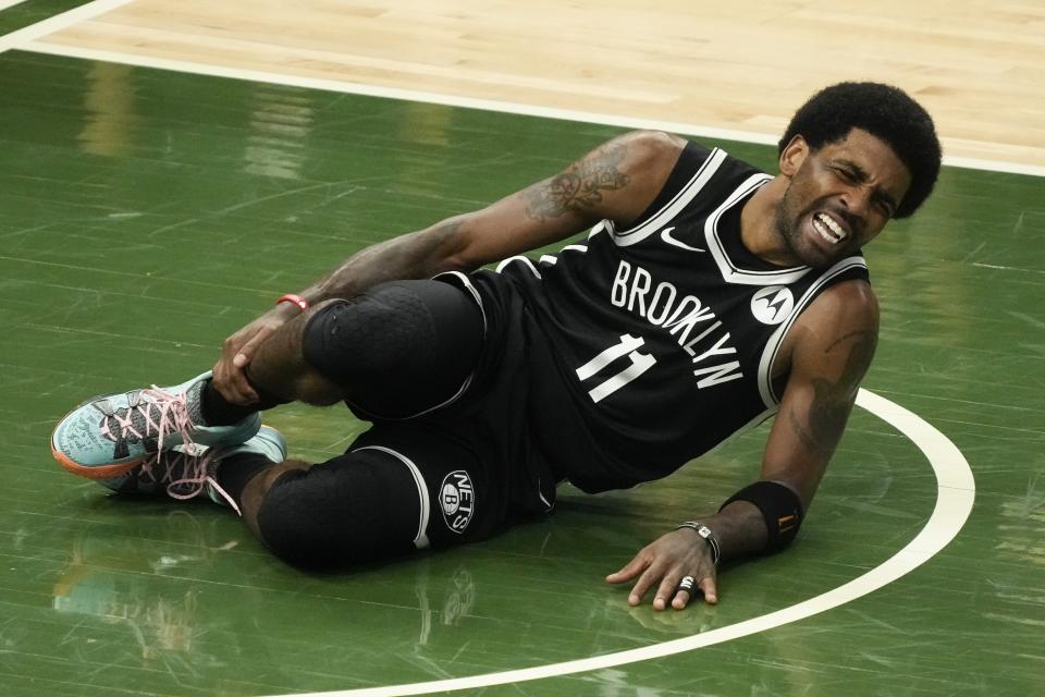 Brooklyn Nets' Kyrie Irving holds his leg after being injured during the first half of Game 4 of the NBA Eastern Conference basketball semifinals game against the Milwaukee Bucks Sunday, June 13, 2021, in Milwaukee. (AP Photo/Morry Gash)