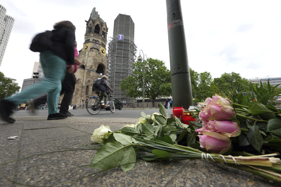 People walk past flowers and candles at the Kaiser Wilhelm Memorial Church in Berlin, Germany, Thursday, June 9, 2022. On Wednesday June 8, a 29-year-old man drove his car into a group of students killing their teacher and crash into a store. (AP Photo/Michael Sohn)