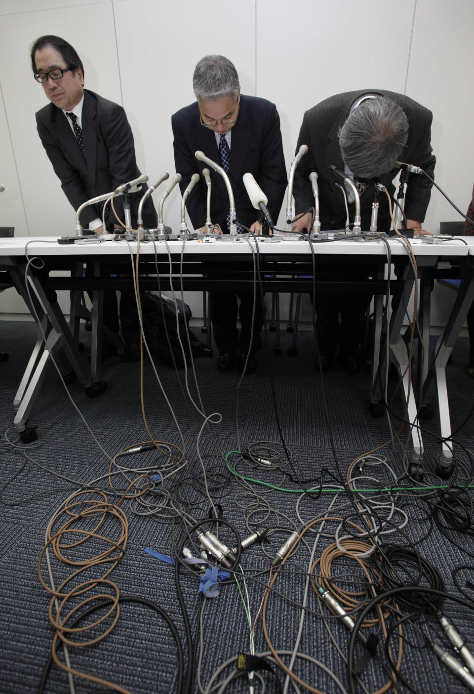 Japanese computer chipmaker Elpida Memory Inc. President Yukio Sakamoto, center, bows at the end of a press conference in Tokyo Monday, Feb. 27, 2012. Elpida filed for bankruptcy Monday after amassing debts from nose-diving prices, longtime competition from Samsung and the flooding in Thailand last year that stagnated demand. (AP Photo/Shizuo Kambayashi)