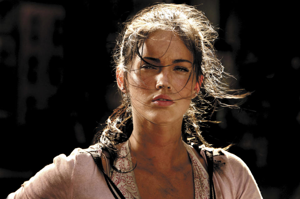 Megan Fox in a movie scene, with messy hair and a serious expression, wearing a casual outfit