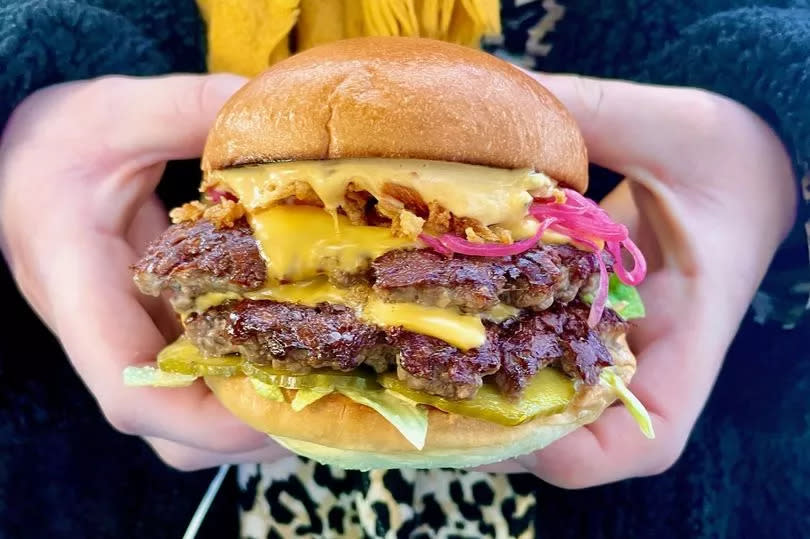 A person holding a tasty looking cheeseburger from Zephyr Burgers.