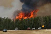 A wildfire burns as evacuees who were stranded north of Fort McMurray, Alberta, Canada head south of Fort McMurray on Highway 63, May 6, 2016. REUTERS/Chris Wattie/File Photo