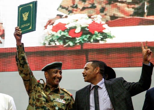 Sudan's protest leader Ahmad Rabie (R), flashes the victory gesture alongside General Abdel Fattah al-Burhan (L), the chief of Sudan's ruling Transitional Military Council after signing the landmark "constitutional declaration" to civil rule