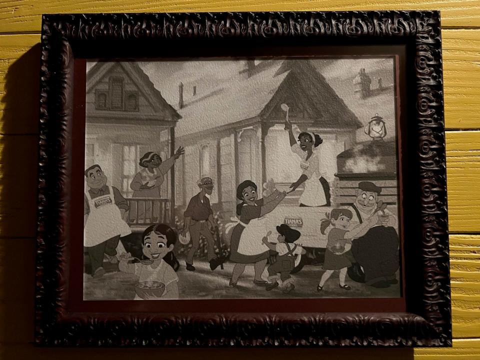 A photo on the wall in the ride queue shows Tiana sharing food with her community through Tiana's Foods. Edgar 'Dook' Chase IV says Dooky Chase still does that in New Orleans.