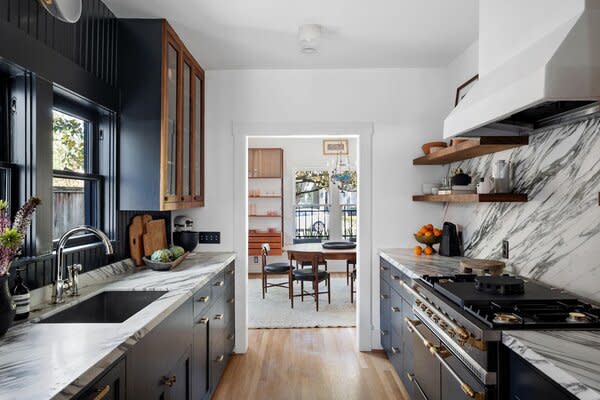 The galley-style kitchen is fitted with custom Black walnut cabinets, which pop against the marble countertops and backsplash. The sun-filled dining room is located just steps away.