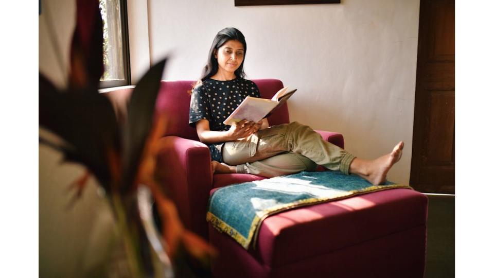 Woman sitting relaxed with legs stretched on a sofa couch and reading a book