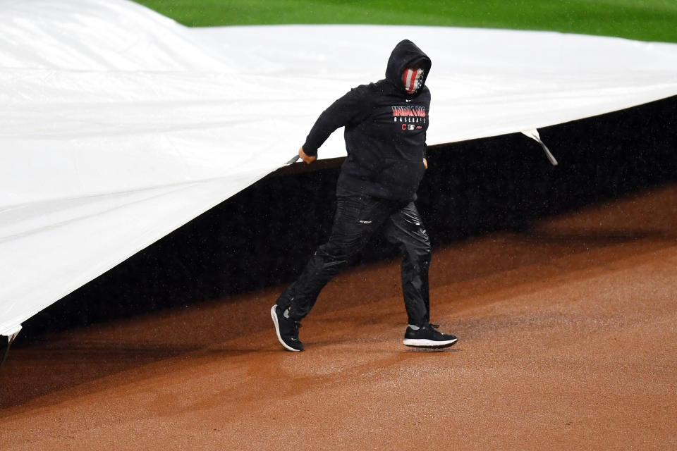 A member of the grounds crew pulls the tarp on the field during a rain delay during Game 2 of the wild-card series in Cleveland. (Photo by Joe Sargent/MLB Photos via Getty Images)