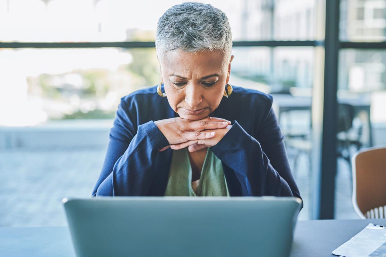 Sad, unhappy and tired business woman browsing online on a laptop, reading an email with bad news or suffering from burnout while sitting in an office. Mature female boss dealing with a work problem