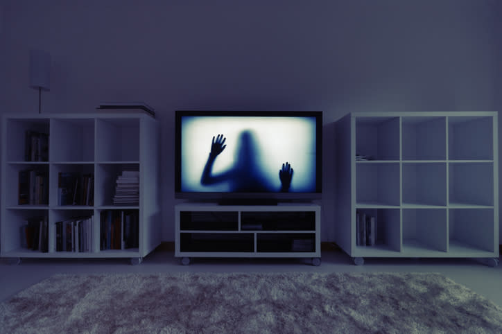 Living room setup with a TV showing a silhouette of a person with hands pressed against the screen, flanked by two bookshelves on either side