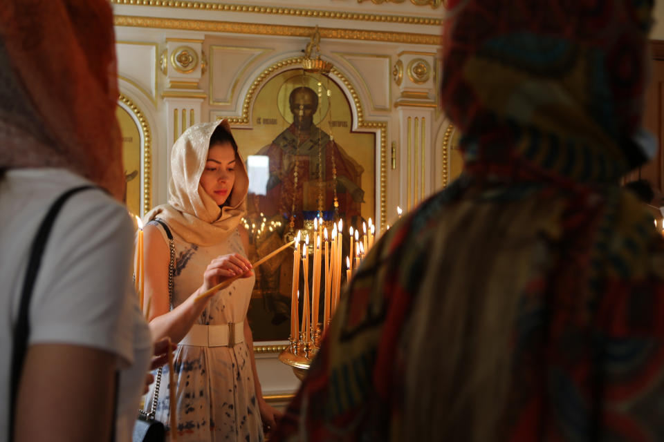 A Russian-speaking expat celebrating Easter lights a candle at the Christian Orthodox Church in Sharjah, United Arab Emirates, Sunday, April 24, 2022. Hundreds of Russians and Ukrainians alike crowded into the only Russian Orthodox Church on the Arabian Peninsula on Sunday to celebrate the most important Christian religious festival of the year — far from home and in the shadow of a war that has brought devastation to Ukraine and international isolation to Moscow. (AP Photo/Isabel Debre)