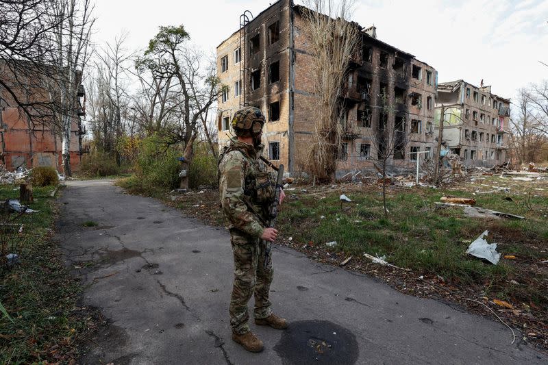 Ukrainian serviceman stands next to residential buildings heavily damaged by permanent Russian military strikes in the front line town of Avdiivka