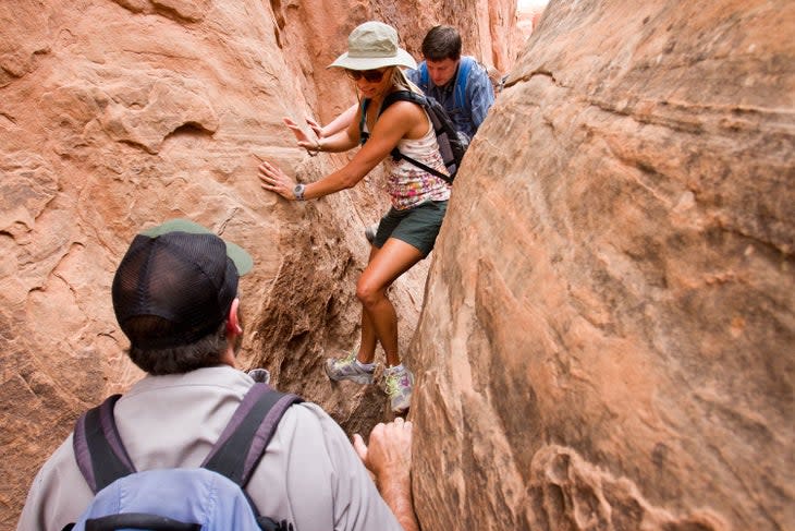 Hikers squeezing through tight canyon walls in the Fiery Furnace of Arches National Park