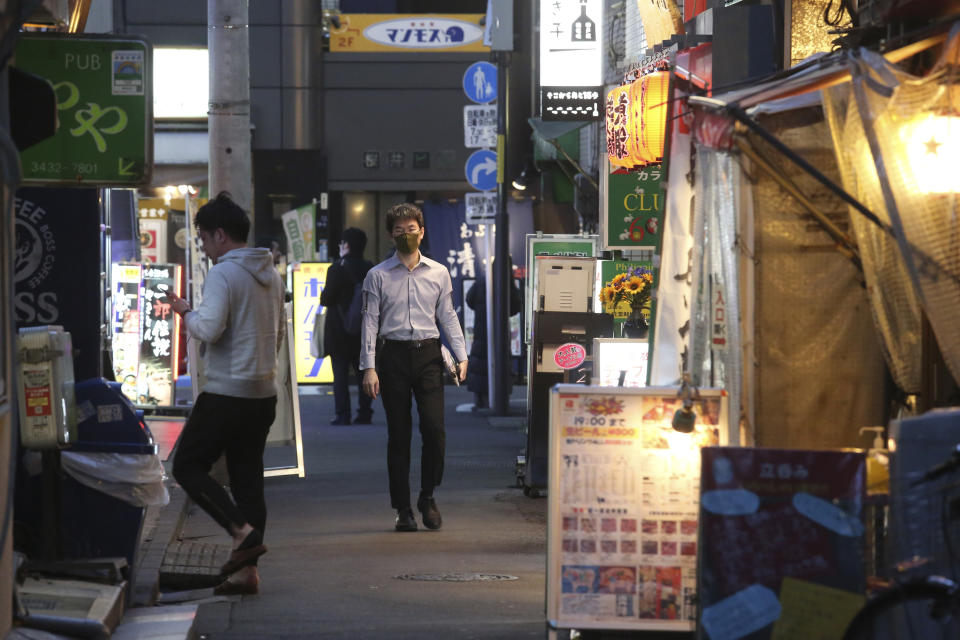 People wearing face masks to protect against the spread of the coronavirus walk on a street lined with bars and restaurants in Tokyo Wednesday, March 16, 2022. Japan’s Prime Minister Fumio Kishida on Wednesday announced plans to fully lift coronavirus restrictions on March 21 as new infections driven by the highly contagious omicron variant slow. (AP Photo/Koji Sasahara)