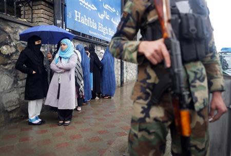 A policeman stands guard outside a polling station in Kabul as Afghans wanting to vote queue outside before it opened April 5, 2014. REUTERS/Tim Wimborne