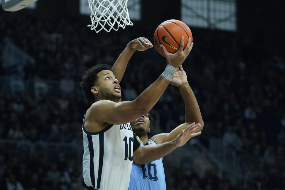 Butler's Bryce Nze, left, shoots against Marquette's Justin Lewis, right, during the first half of an NCAA college basketball game, Saturday, Feb. 12, 2022, in Indianapolis. (AP Photo/Darron Cummings)