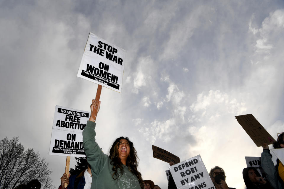 People hold up signs reading Stop the war on women, Free abortion on demand, and Defend Roe by any means necessary.