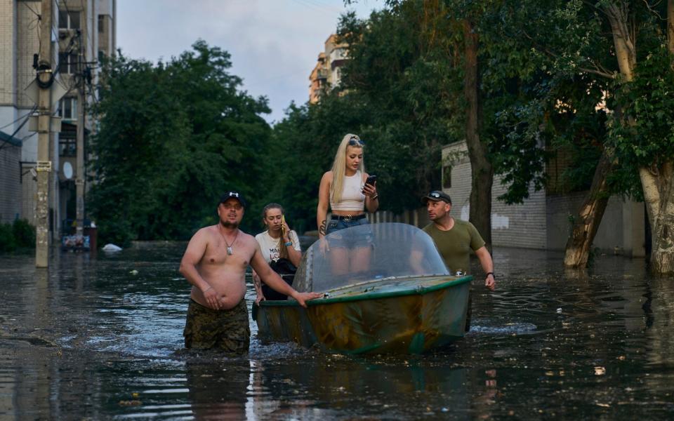 Rescue workers attempt to tow boats carrying residents being evacuated from a flooded neighborhood in Kherson - Libkos/AP