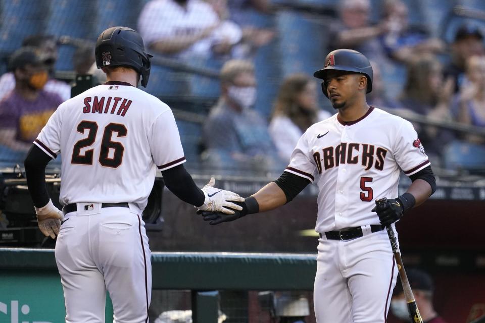 Arizona Diamondbacks' Pavin Smith (26) celebrates his run scored against the Miami Marlins with teammate Eduardo Escobar (5) during the first inning of a baseball game Monday, May 10, 2021, in Phoenix. (AP Photo/Ross D. Franklin)