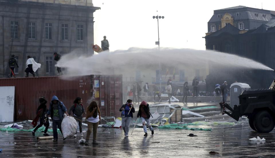 A police water cannon disperses anti-government protesters during a nationwide strike, at Bolivar square in downtown Bogota, Colombia, Thursday, Nov. 21, 2019. Colombia's main union groups and student activists called for a strike to protest the economic policies of Colombian President Ivan Duque government and a long list of grievances. (AP Photo/Fernando Vergara)