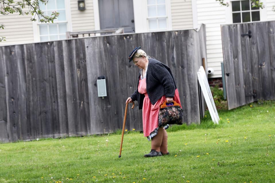 A Strawbery Banke roleplayer walks across the lawn to one of the historic homes in Portsmouth on her way to work Wednesday, May 15, 2024.