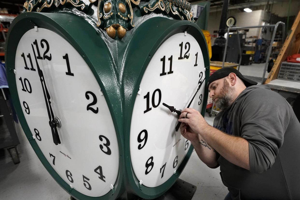 Ahead of the end of Daylight Saving Time on Nov. 7, a technician adjust an outdoor clock under construction at Electric Time Company, in Medfield, Mass. [AP PHOTO/STEVEN SENNE/FILE]