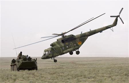 An MI-17 helicopter flies by an armoured personnel carrier (APC) during the Steppe Eagle 2010 joint tactical military exercise at Ili military range, outside Almaty in this August 24, 2010 file photo. REUTERS/Shamil Zhumatov/Files