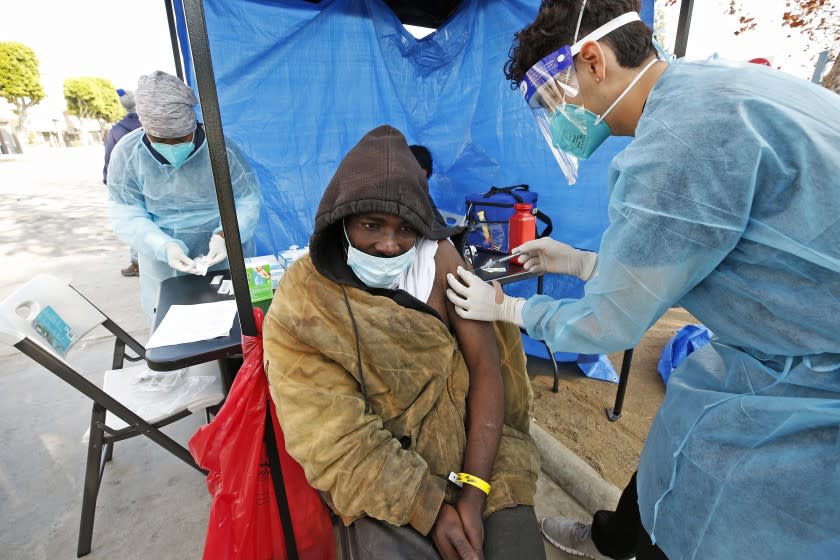 LOS ANGELES, CA - FEBRUARY 08: Registered nurse Kevin Hernandez, right, delivers a Covid-19 vaccine to Kerry Cahee, 34, as Los Angeles County Department of Health Services Housing for Health Program administered the Covid-19 vaccinations for persons experiencing homelessness (PEH) at Leimert Park Plaza located at Crenshaw Blvd and West Vernon Ave Monday. Vaccinations began last week building off COVID-19 response work with PEH that relies on the trust developed with the community. DHS' program, Housing for Health, was established in 2012 and provides a continuum of services to people experiencing homelessness who have complex health and/or behavioral health conditions. DHS implemented a COVID-19 testing program in April for people experiencing homelessness in sheltered and unsheltered settings. Leimert Park on {what} in Los Angeles, CA. (Al Seib / Los Angeles Times).