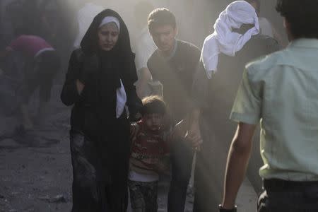 An injured woman and boy flee a site hit by what activists said were two airstrikes by forces loyal to Syria's President Bashar al-Assad in Douma in eastern al-Ghouta, near Damascus August 3, 2014. REUTERS/Badra Mamet