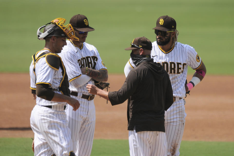 San Diego Padres manager Jayce Tingler, middle, talks with catcher Jason Castro, left, Manny Macho, middle, and Fernando Tatis Jr., right, during a pitching change against the Los Angeles Dodgers in the third inning of a baseball game Wednesday, Sept. 16, 2020, in San Diego. (AP Photo/Derrick Tuskan)