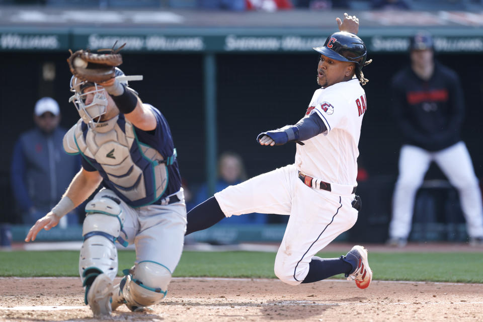 Cleveland Guardians' Jose Ramirez, right, scores the game winning run past Seattle Mariners catcher Cal Raleigh on a fielders choice by Josh Bell during the 12th inning of a baseball game, Sunday, April 9, 2023, in Cleveland. (AP Photo/Ron Schwane)