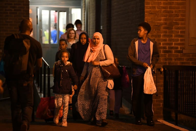 A family leave the Taplow Tower residential block on the Chalcots Estate in north London on June 23, 2017 as residents are evacuated because of fire safety concerns