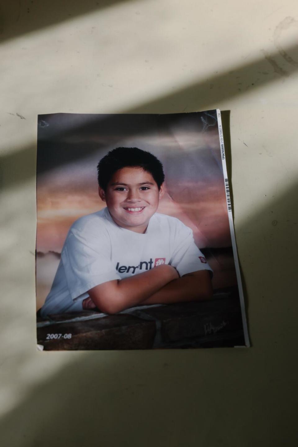 A portrait of a boy leaning forward with his arms crossed in front of a sunset backdrop