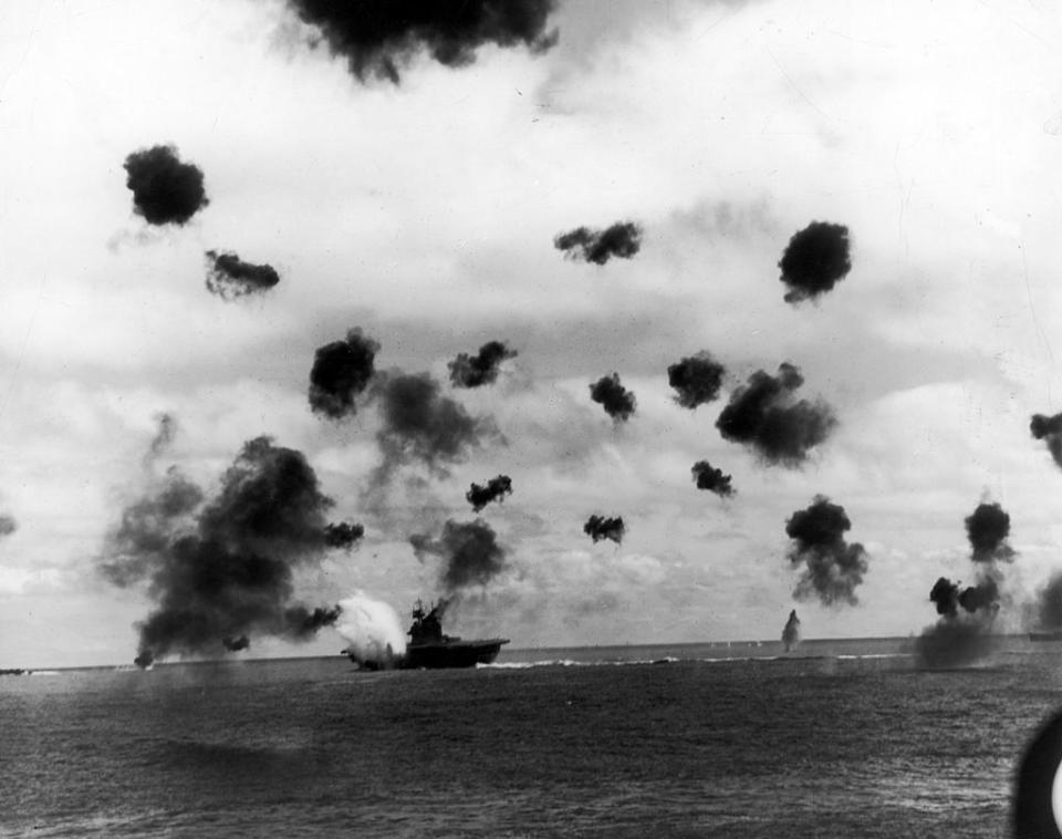 Smoke from antiaircraft guns fills the sky as aircraft carrier USS Yorktown (rear, C) is hit by a Japanese torpedo during the Battle of Midway on June 6, 1942. | US Navy/The LIFE Picture Collection—Getty Images