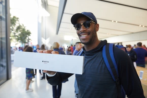 An excited customer holds an Apple Watch 3 Series in a box at an Apple Store