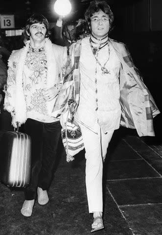 <p>Bettmann/Getty</p> Ringo Starr and John Lennon walk through a train station in London together in 1967.
