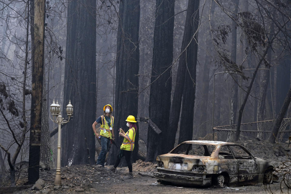 Workers with Davey Resource Group survey the damage to the trees in a neighborhood Tuesday, Aug. 25, 2020, in Boulder Creek, Calif., after the the CZU August Lightning Complex Fire passed by. (AP Photo/Marcio Jose Sanchez)