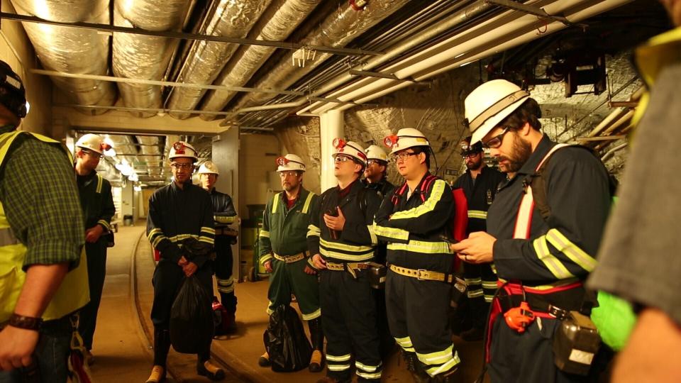 Researchers at the Sanford Underground Research Facility in Lead, S.D., discuss conditions on Dec. 8, 2019 at the underground laboratory that was once used as a gold mine. Scientists have begun a new search for mysterious dark matter in a former gold mine a mile underground. Dark matter makes up the vast majority of the mass of the universe but scientists don't know what it is. (AP Photo/Stephen Groves)