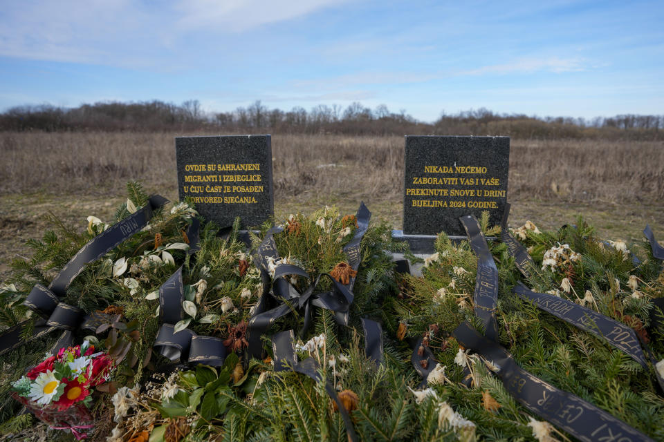 The memorial with an inscription that reads: "Migrants and refugees in whose memory these trees were planted are buried here; we will never forget you and your dreams interrupted in the Drina" is seen at the cemetery in Bijeljina, eastern Bosnia, Sunday, Feb. 4, 2024. In several cities along this river between Bosnia and Serbia, simple, durable gravestones now mark the final resting places of dozens of refugees and migrants who drowned in the area while trying to reach Western Europe. (AP Photo/Darko Vojinovic)