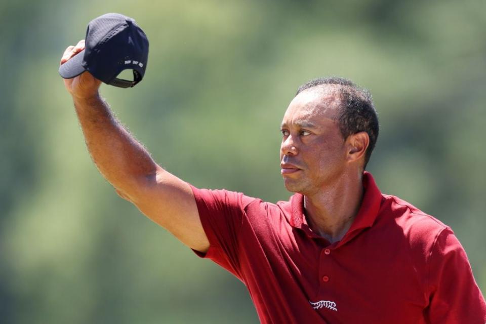 Tiger Woods tips his hat to the crowd while walking to the 18th green.