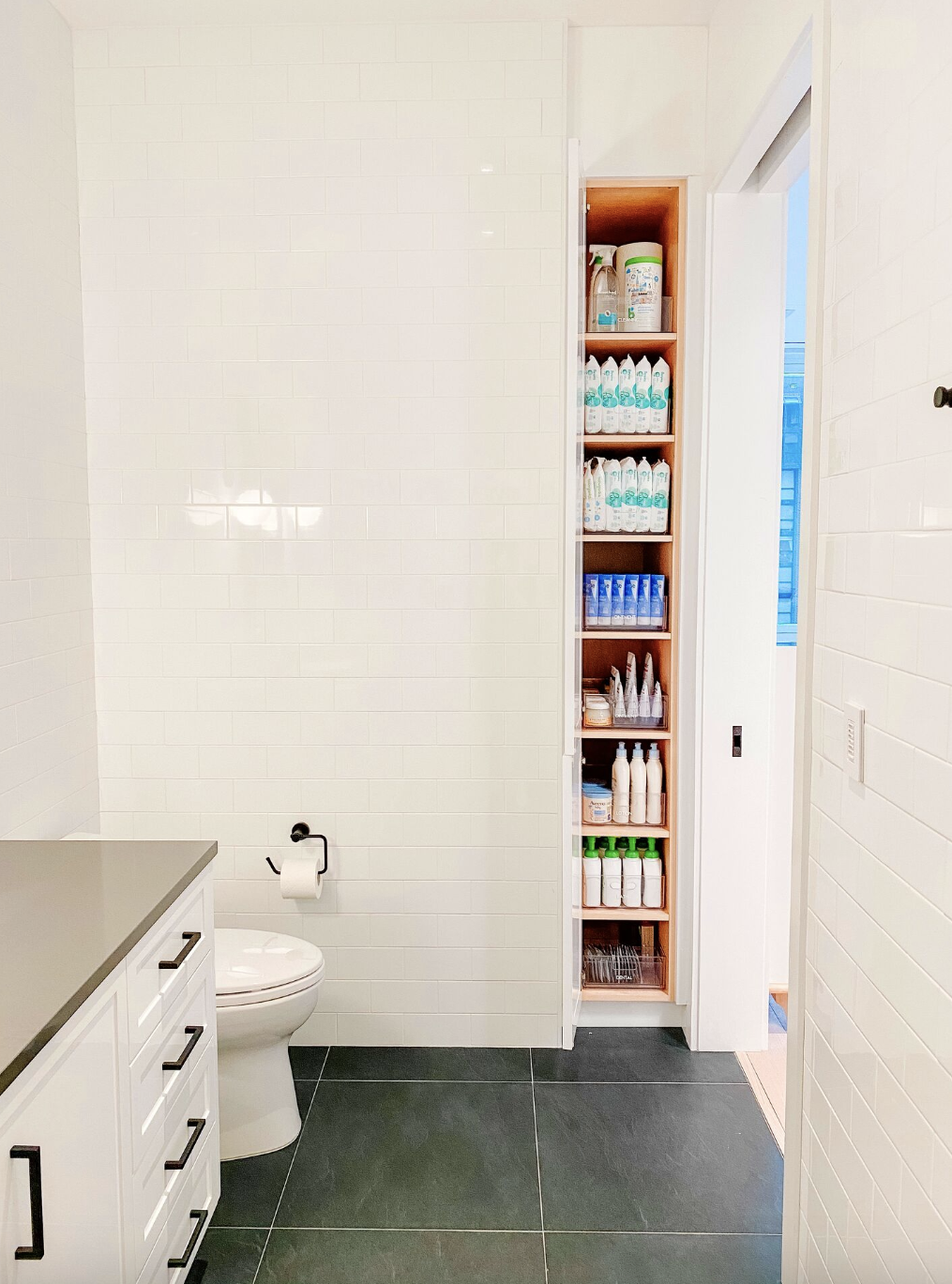 bathroom storage ideas, thin cabinet open to reveal bath products