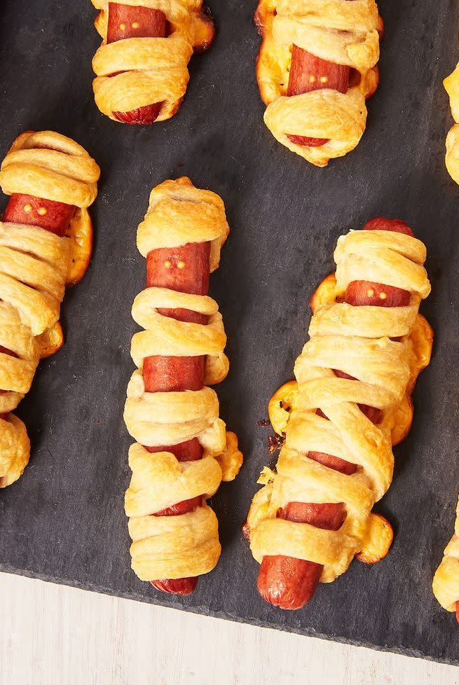 <p>This kid-friendly Halloween appetizer will have them going for seconds. These delicious mummy hot dogs are stuffed with cheese and bakes with Crescent dough — yum!</p><p>Get the <strong><a href="https://www.delish.com/holiday-recipes/halloween/a28621353/mummy-hot-dogs-recipe/" rel="nofollow noopener" target="_blank" data-ylk="slk:Mummy Hot Dogs recipe;elm:context_link;itc:0;sec:content-canvas" class="link ">Mummy Hot Dogs recipe</a></strong> from Delish. </p>