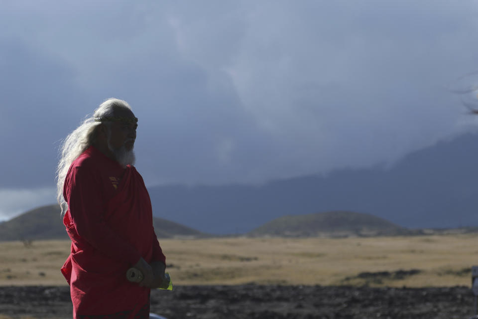 A native Hawaiian activist prays at the base of Hawaii's Mauna Kea on Sunday, July 14, 2019. Hundreds of demonstrators gathered at the base of Hawaii's tallest mountain to protest the construction of a giant telescope on land that some Native Hawaiians consider sacred. State and local officials will try to close the road to the summit of Mauna Kea Monday morning to allow trucks carrying construction equipment to make their way to the top. Officials say anyone breaking the law will be prosecuted. Protestors have blocked the roadway during previous attempts to begin construction and have been arrested. (AP Photo/Caleb Jones)