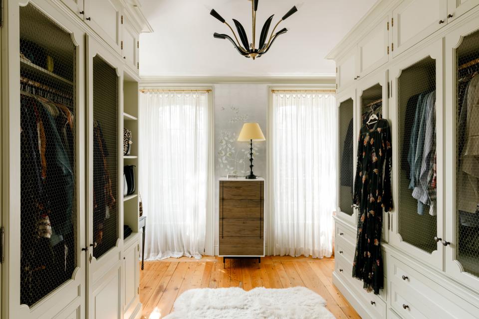 The entire top floor serves as a master suite, which includes this light-filled and expansive walk-in closet. “It’s a his-and-hers closet, but I’ve taken over both of them,” says Tyler. Her husband, British sports agent Dave Gardner (and the father of Tyler’s youngest children, Sailor and Lula), keeps the majority of his things in their other home, a West London townhouse. Chicken-wire panels allow closet doors to remain transparent. “We were originally going to put fabric behind the chicken wire,” says Tyler. “Then we moved in and I really liked it open, so we never put the fabric in. The room has little secret drawers and lots of fun little details throughout.” The silver leaf wallpaper is vintage de Gournay. “On the lower portion [of the pattern] there are images of a Chinese countryside,” recalls Tyler. I cropped it just above so we could have only flowers.” The chandelier, one of a bunch of similar pieces Tyler has hanging throughout the home, is a vintage midcentury Italian design. The dress hanging at right is also vintage.