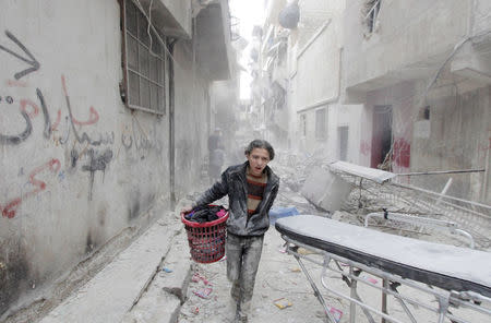 A boy carries his belongings at a site hit by what activists said was a barrel bomb dropped by forces loyal to Syria's President Bashar al-Assad in Aleppo's al-Fardous district, Syria April 2, 2015. REUTERS/Rami Zayat/File Photo
