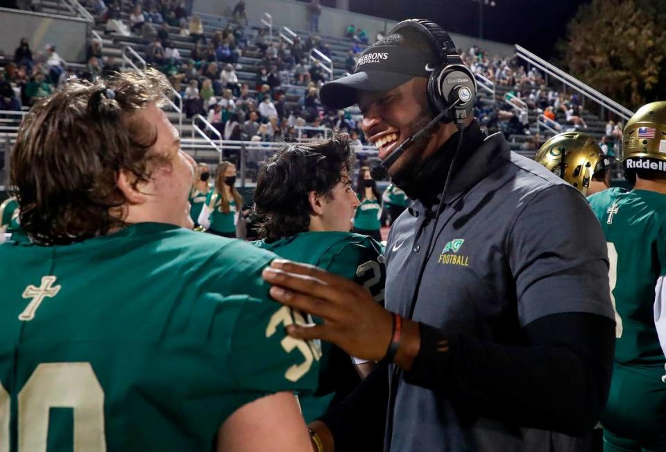 N.C. State linebacker Isaiah Moore celebrates with Cardinal Gibbons High School’s Carter Scearce (30) during the Crusaders’ game against Pine Forest in Raleigh, N.C., Friday, April 16, 2021. Moore is doing a minor at State in coaching. Part of the curriculum required a certain amount of intern hours getting real life coaching experience, which led Moore to volunteer coach at Gibbons this season.